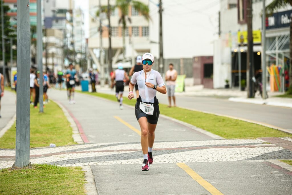 A determined woman running a triathlon race in an urban setting, wearing sportswear.
